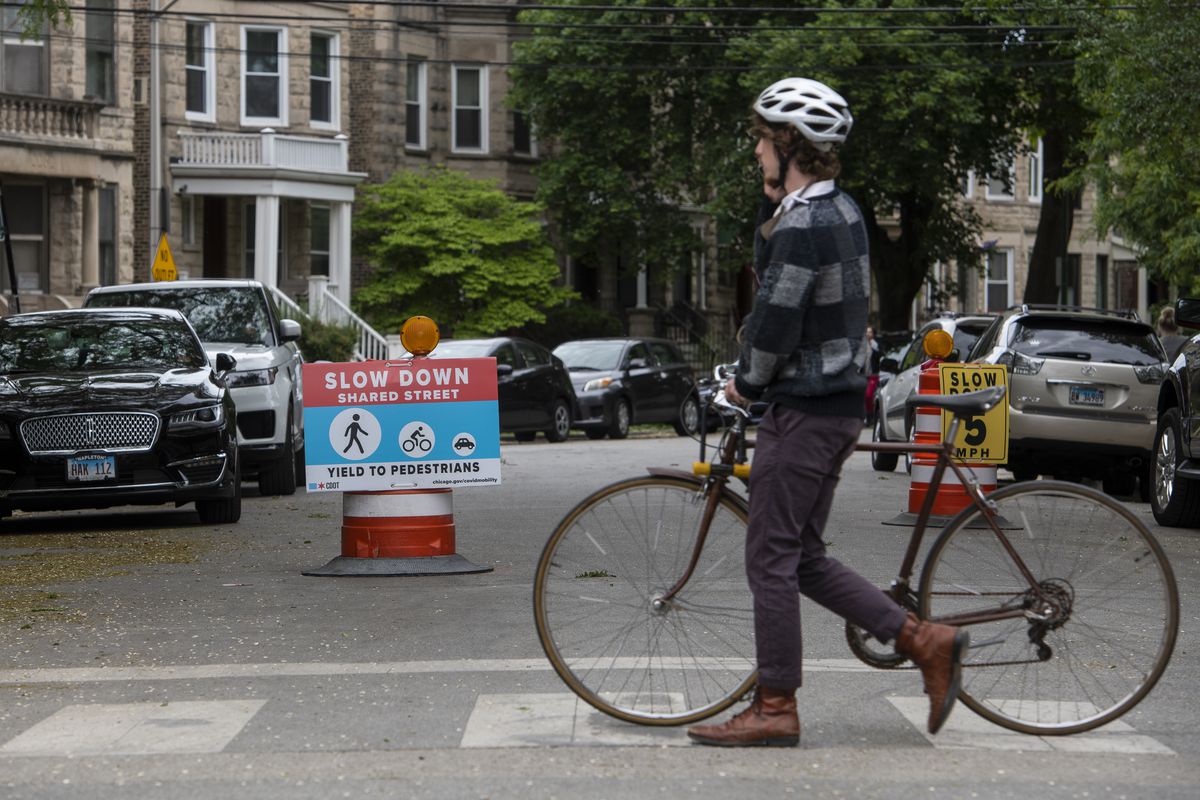 A cyclist walks their bike by a “Shared Street” located at North Lincoln Ave. and West Leland Ave. in the Lincoln Square neighborhood, Thursday, May 27, 2021. This is the second year this street has been designated as a “Shared Street” by the Chicago Department of Transportation.