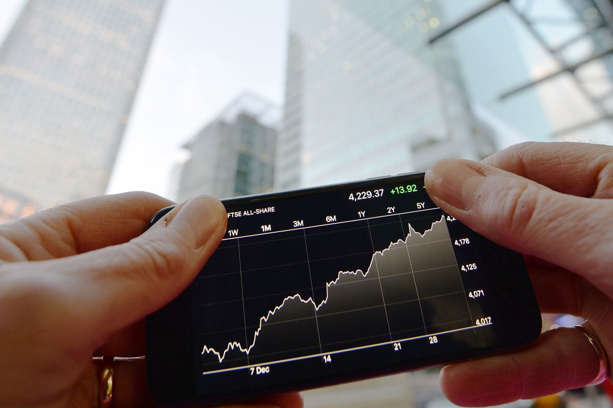  A person looks at share prices on a smartphone