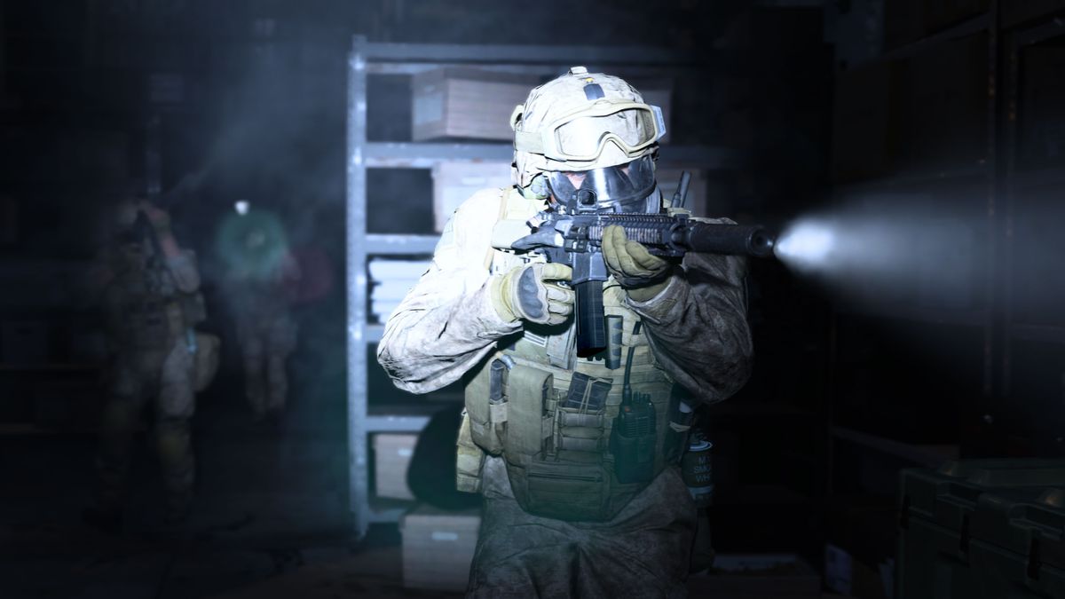 A soldier moves through a dark room, a flashlight attached to his gun