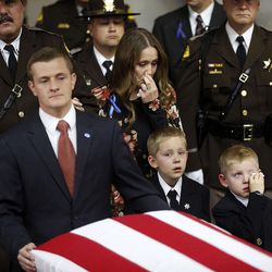 Janica Ellsworth, center, along with sons Bennett, left, and Ian, right, accompany the casket of their husband and father, Utah Highway Patrol trooper Eric Ellsworth, into the Dee Events Center in Ogden on Wednesday, Nov. 30, 2016.