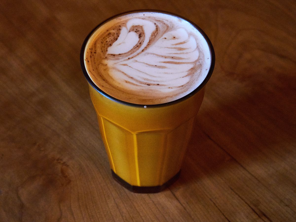 A yellow-tinged latte in a tall clear glass.