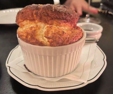 A cheese souffle puffs from its ceramic container at Koloman, a new restaurant in Nomad.