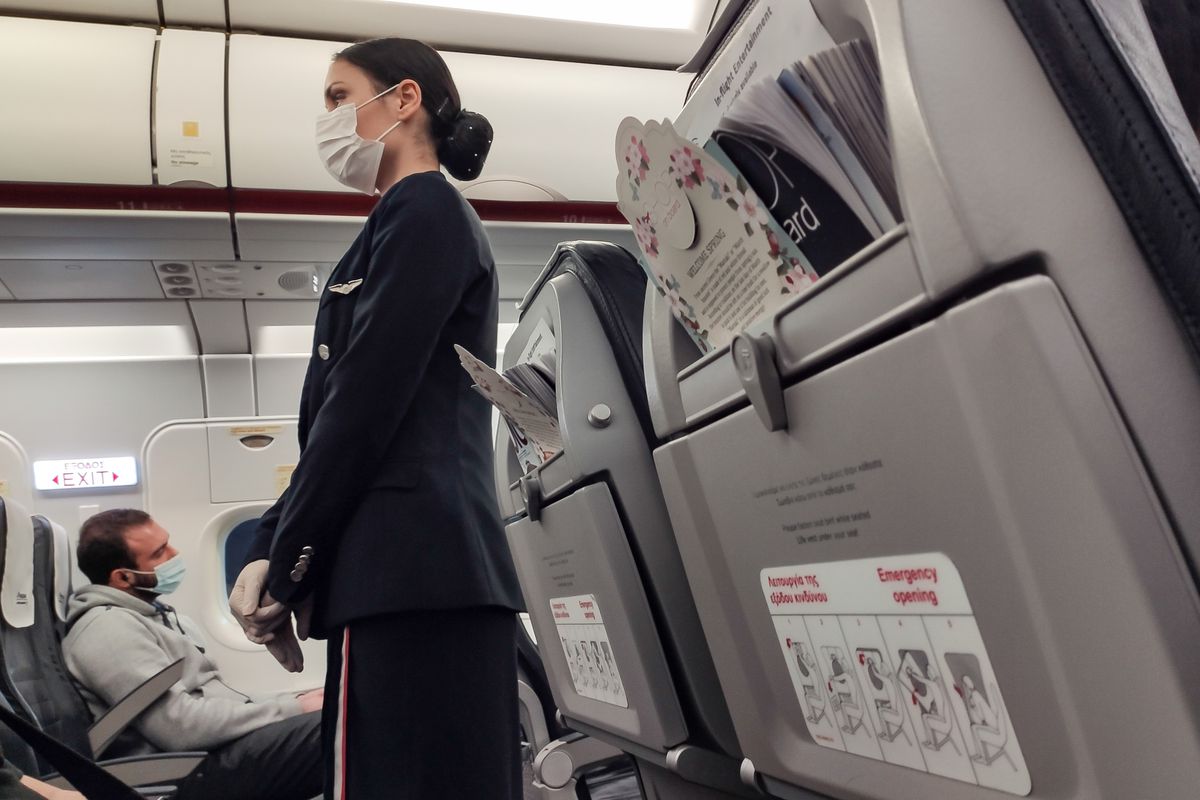 A flight attendant wearing a breathing mask.