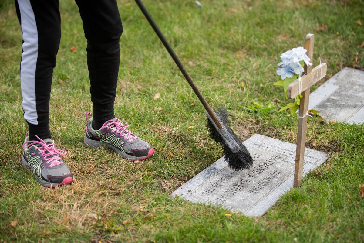 Sandra Bartusiak, 79, of Plainfield, sweeps the graves of her late husband and in-laws at St. Mary Catholic Cemetery in Evergreen Park.