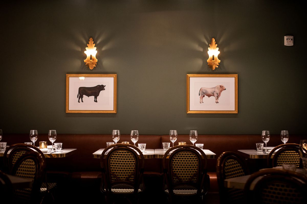 A dim evening restaurant with green walls and images of cattle.