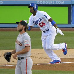 Los Angeles Dodgers' Yasiel Puig, right, runs to first as he hits a solo home run San Francisco Giants starting pitcher Madison Bumgarner watches during the first inning of their baseball game, Monday, June 24, 2013, in Los Angeles.  