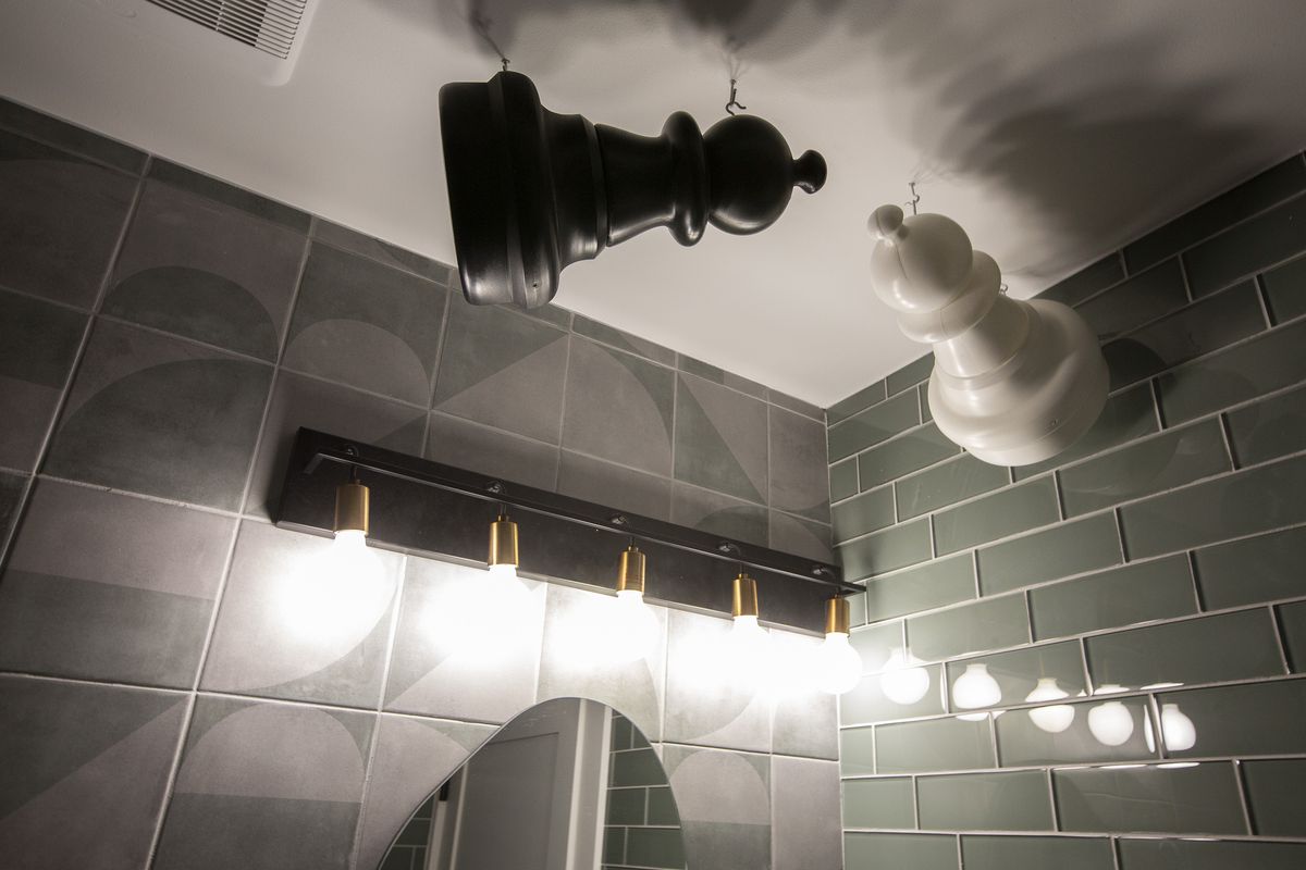 Two oversize chess pieces hang from a bathroom ceiling.