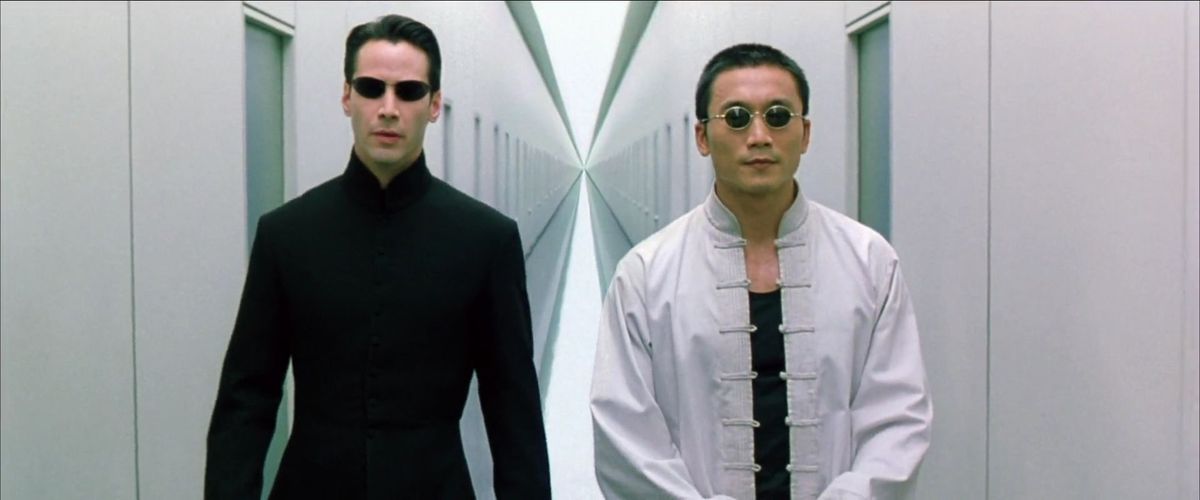 Seraph and Neo walk down a white hallway in The Matrix Reloaded