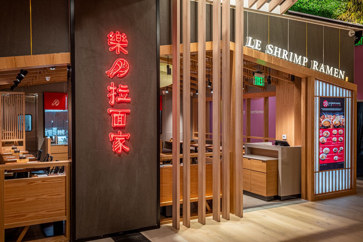 A slightly angled look at a neon-lit wooden restaurant serving ramen.