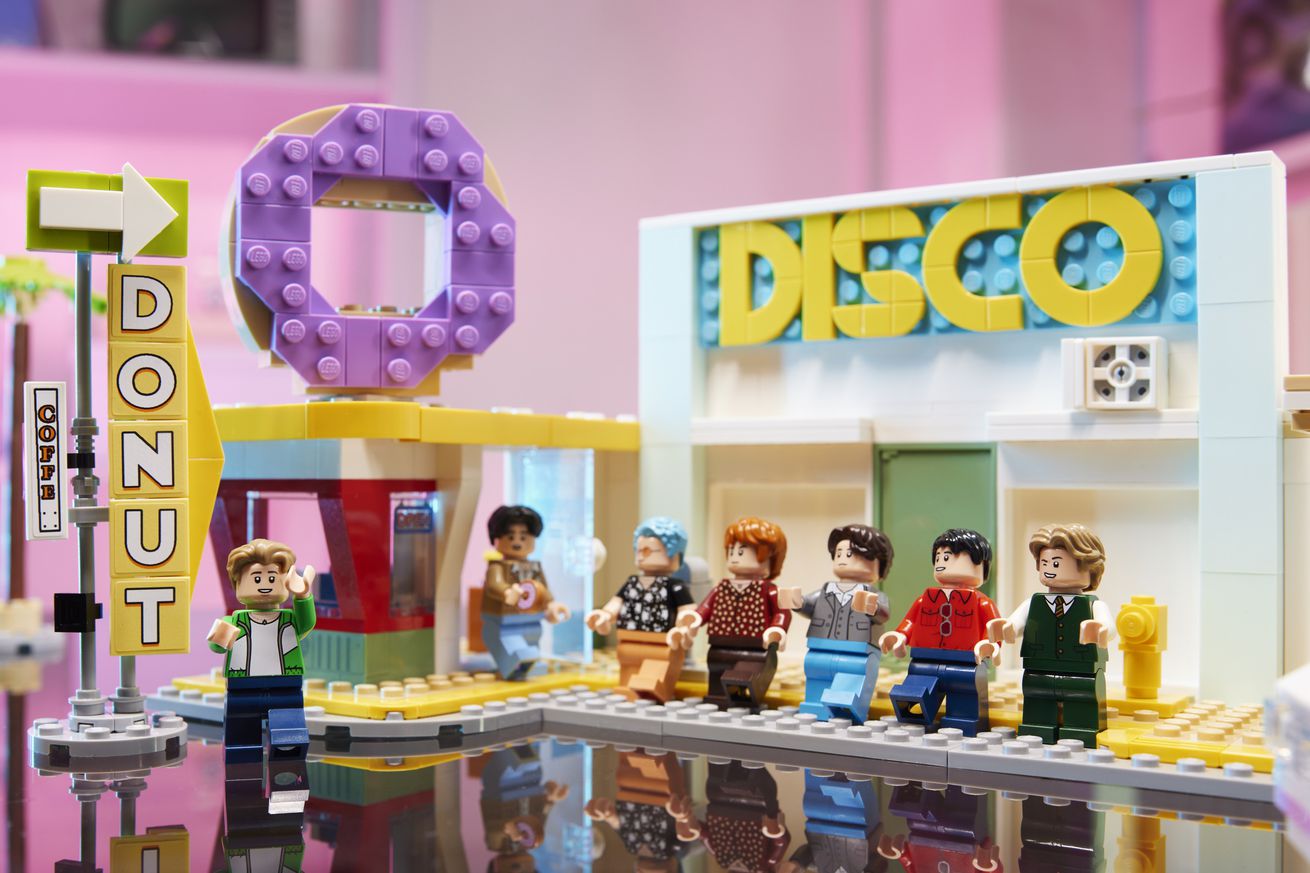 BTS Lego figurines arranged outside a Lego disco and donut shop.