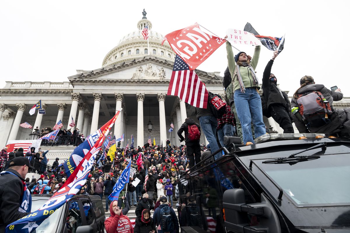 Rioters in front of the US Capitol wave MAGA and Trump flags.