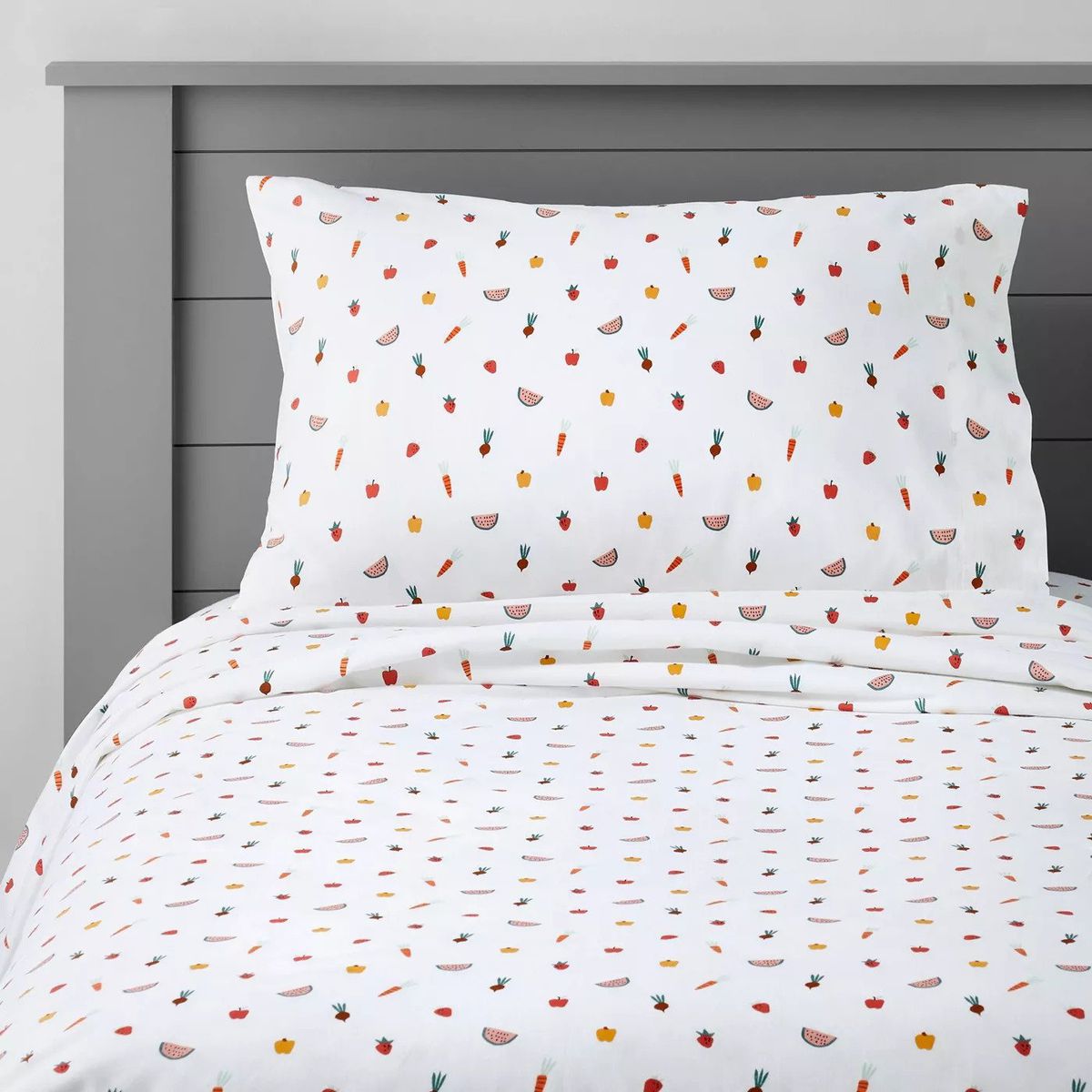 A bed made with sheets in a fruit pattern