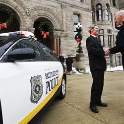 Salt Lake City Mayor Ralph Becker and Police Chief Chris Burbank shake hands after introducing a new hybrid police car to the media as well as an and electric segway type vehicle for use with the city's police force. 