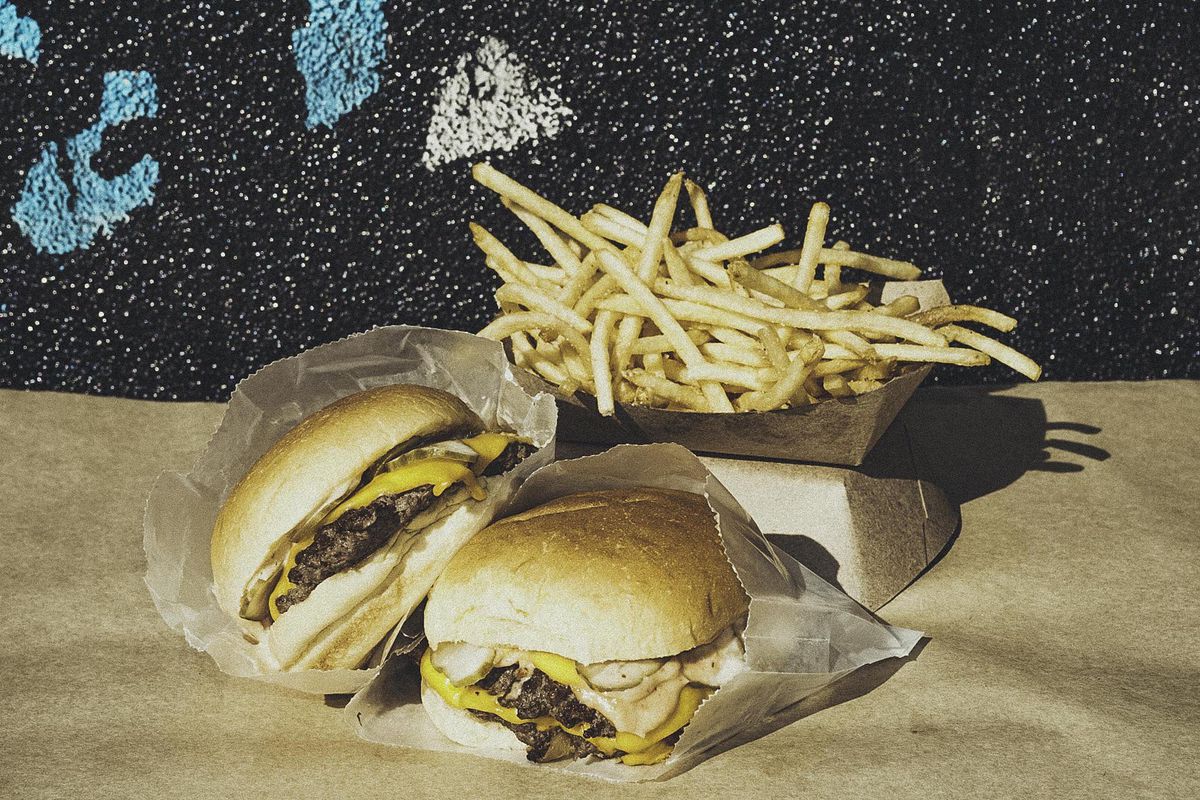 Two burgers with a hip painted background and a large cascade of fries.