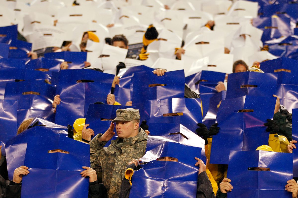 NOVEMBER 12: A member of the Military stands at attention as fans hold up color poster which made up the colors of the American flag during the performance of the National Anthem prior to the Pittsburgh Steelers hosting the Kansas City Chiefs at Hein