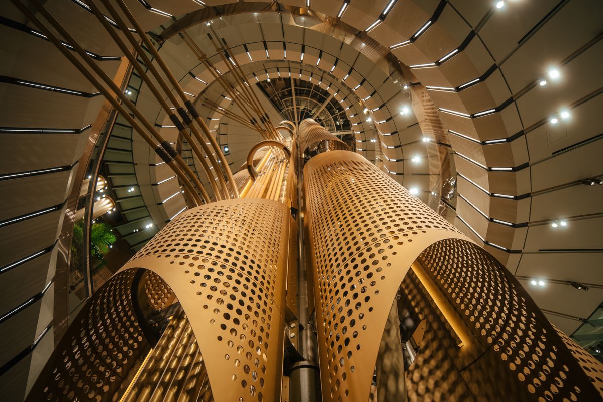 A detail of metal gold cylinders surrounded by a curved escalator.