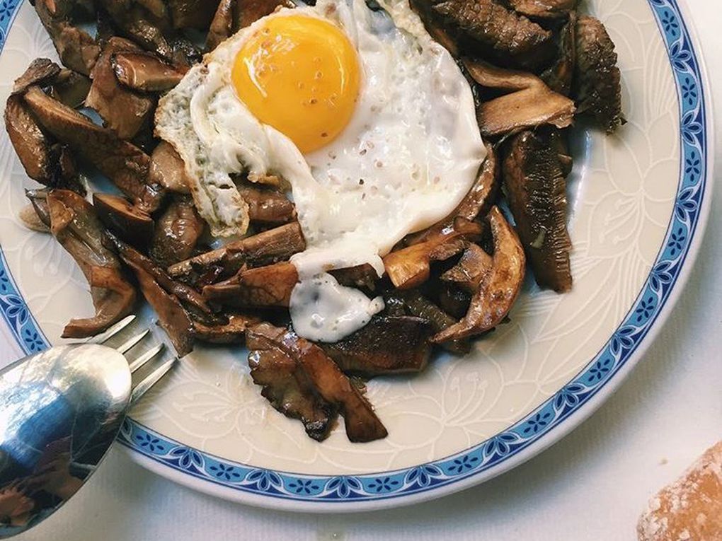 A plate of mushrooms topped with a sunny side up egg.