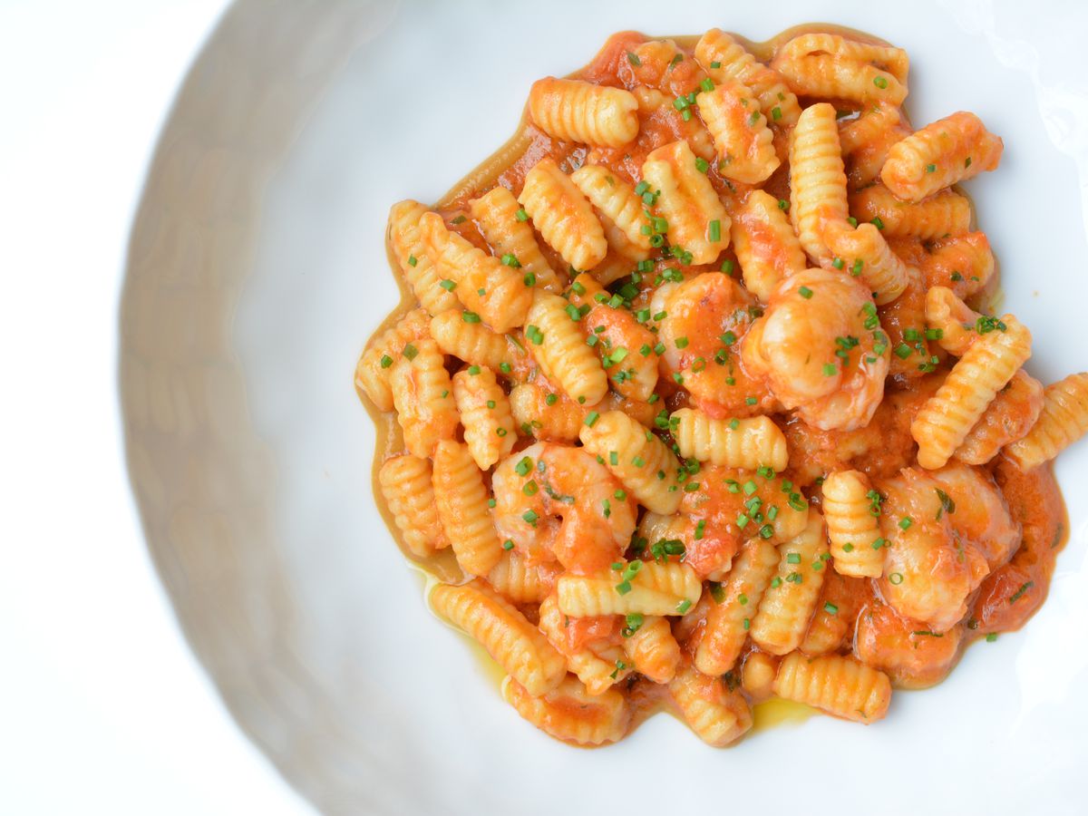 Ridged, oblong gnocchetti sit in a white bowl with a pink-ish tomato sauce