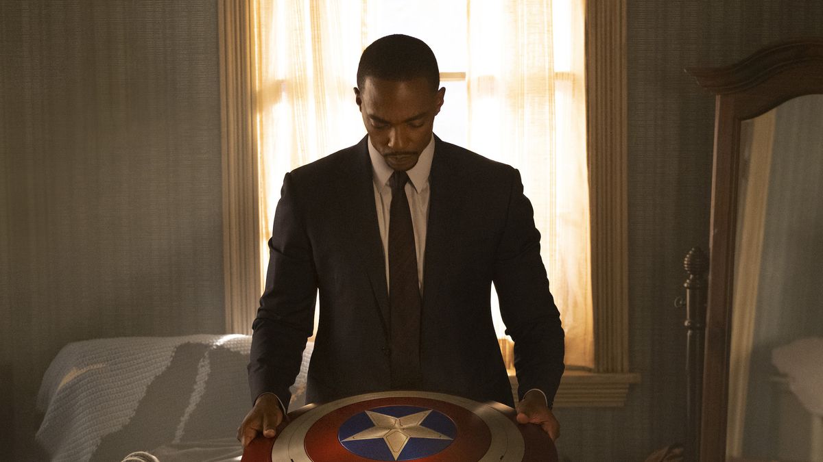 Sam Wilson (Anthony Mackie) stands in front of a window holding Captain America’s shield thoughtfully in Falcon and the Winter Soldier
