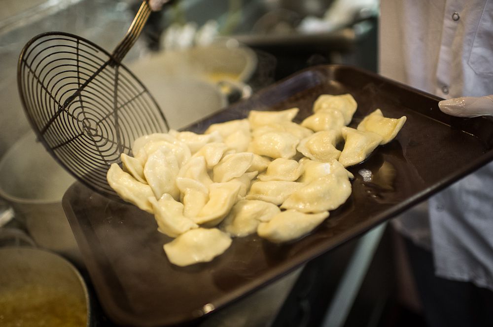 Pierogies—white crescent-shaped dumplings — that have been pulled out fresh from being boiled.