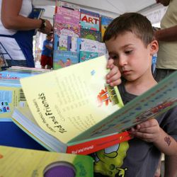 Tyler Marion, age 5, looks at books at the Usborne Books tent at the KSL Family Book Festival at The Gateway in Salt Lake City on Saturday, June 15, 2013.