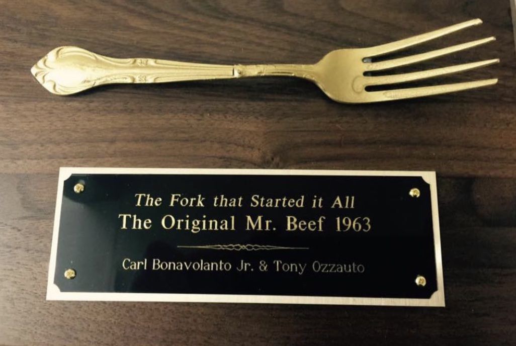 A bronzed fork on a wooden plaque.