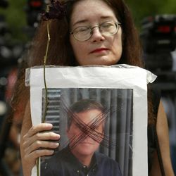 In this March 31, 2005 file photo, Nancy Kramer holds a dead rose and a defaced photograph of  Florida Gov. Jeb Bush, as she stand vigil in front of the Woodside Hospice where Terri Schiavo died in Pinellas Park, Fla. As Jeb Bush prepares for a likely presidential bid, one name seems destined to loom large over his potential campaign: Terri Schiavo. The battle over the fate of the brain-damaged woman from the Tampa Bay-area was a defining moment in Bush"™s governorship, and two events this week suggested that his controversial intervention to keep her alive will remain a political flashpoint.