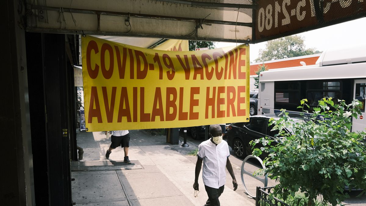 A sign outside a pharmacy reads “Covid-19 vaccine available here.”