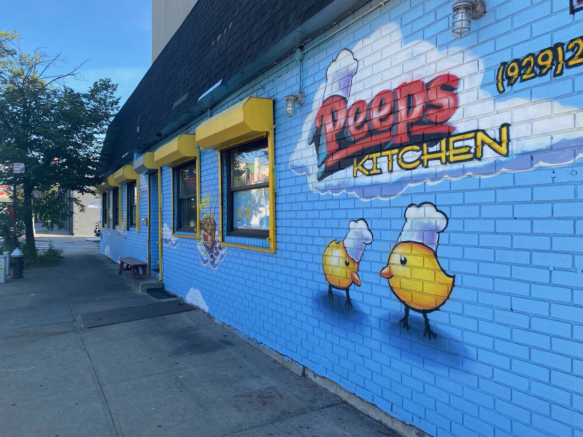 A mural depicts two chickens in chef’s hats grazing against a blue wall.
