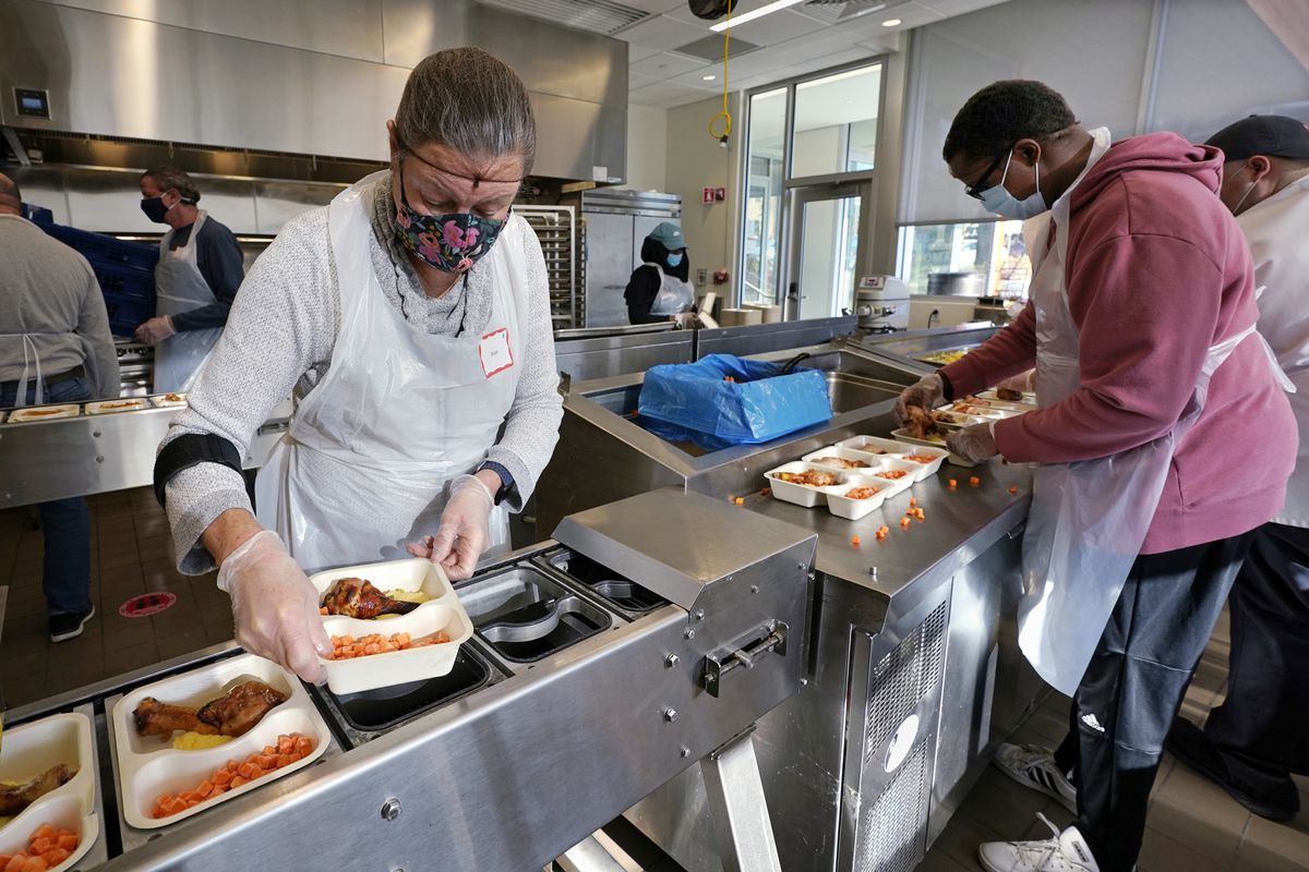 Volunteers Sheeran Howard (left) and Ibrahim Bahrr package meals at Community Servings, which prepares and delivers scratch-made, medically tailored meals to people with severe illnesses in Boston’s Jamaica Plain neighborhood. Insurers first started covering Community Servings meals about five years ago, and CEO David Waters says they now cover close to 40%.