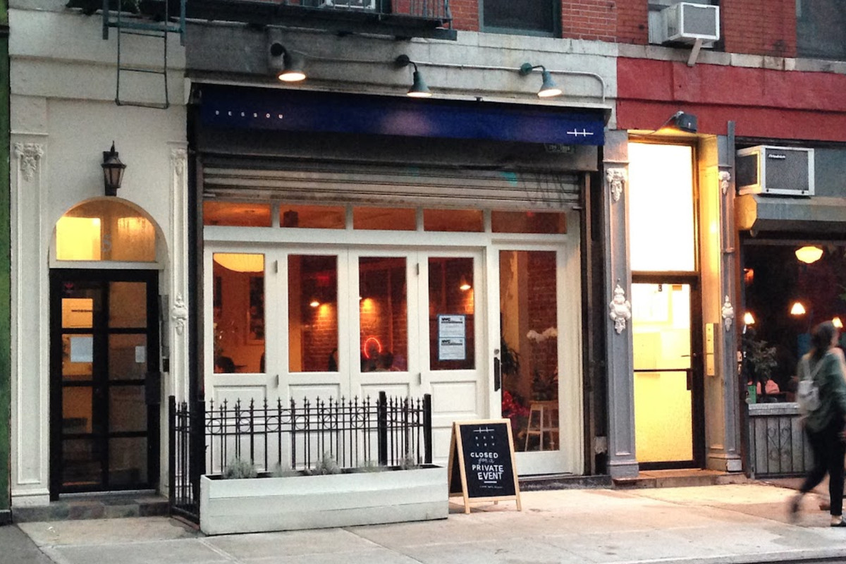 A restaurant storefront with a blue awning, large windows, and a chalkboard sign out front.