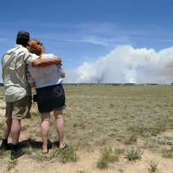 Dave and Linda Burgess watch as a plume rises near their home on Burgess Road in The Black Forest on Wednesday, June 12, 2013 near Colorado Springs, Colo. They were not sure if their home survived the fire.  Three Colorado wildfires fueled by hot temperatures, gusty winds and thick, bone-dry forests have together burned dozens of homes and led to the evacuation of more than 7,000 residents and nearly 1,000 inmates at medium-security prison. (AP Photo/Bryan Oller)