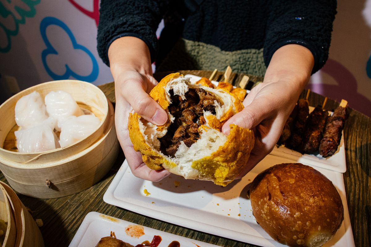 A crusty pineapple bun is cracked in half, revealing a center full of barbecue pork.