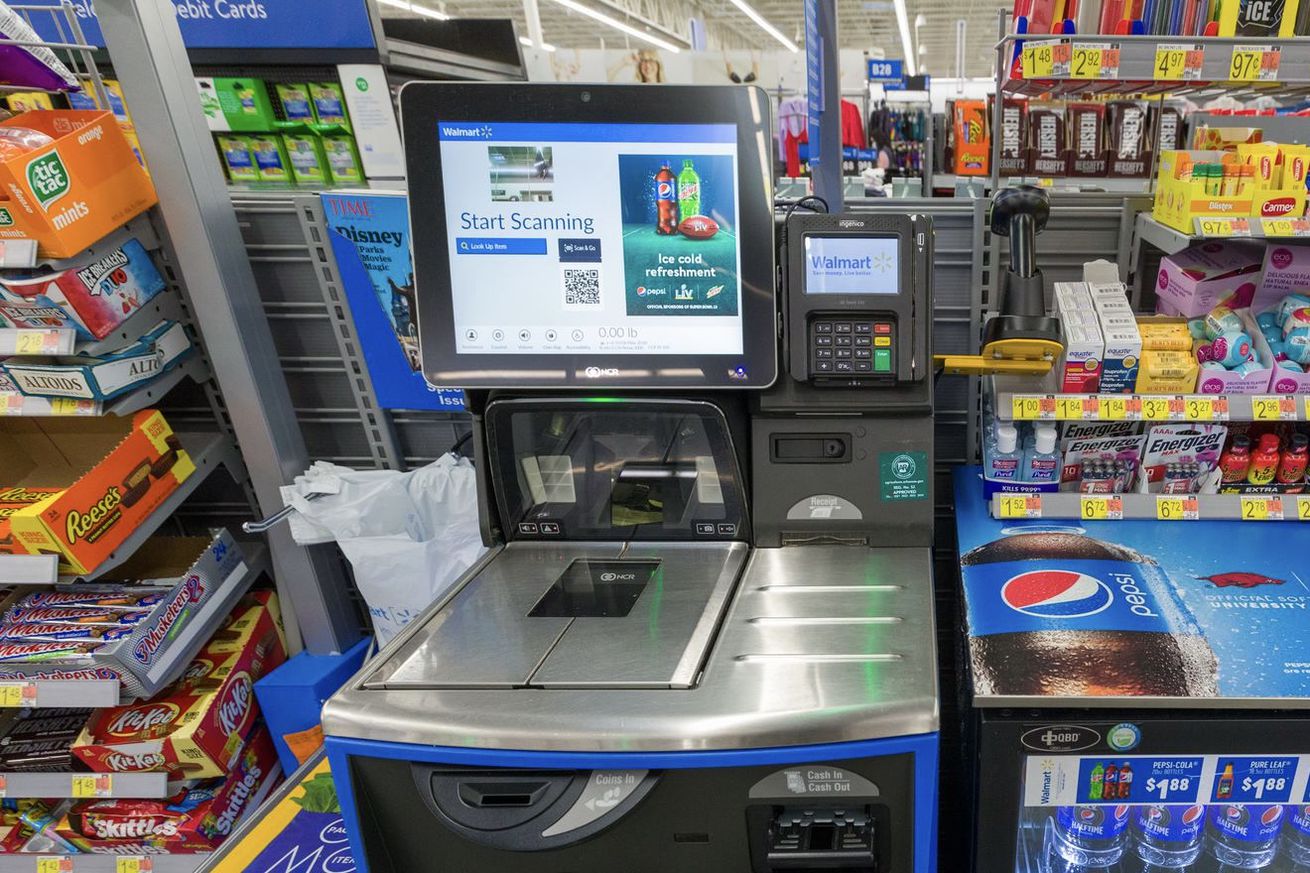 Self-checkout kiosk at a Walmart with the screen saying “start scanning.” Beside it is a Pepsi ad.