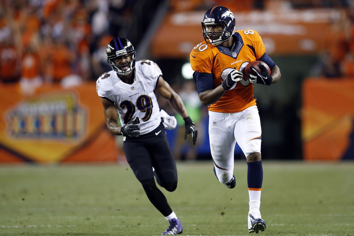 Broncos' TE Julius Thomas catching pass and running with Ravens' S Michael Huff trailing behind him.