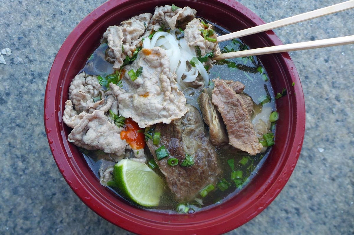 A bowl of soup with two types of beef and chopsticks thrust into the soup.