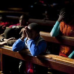FILE - In this Sunday, June 16, 2013, file photo, school children pray in the Regina Mundi church in Soweto township on the outskirt of  Johannesburg, South Africa. On Sunday, June 16, the former South African president Nelson Mandela had remained hospitalized for the ninth day with an occurring lung infection. 
