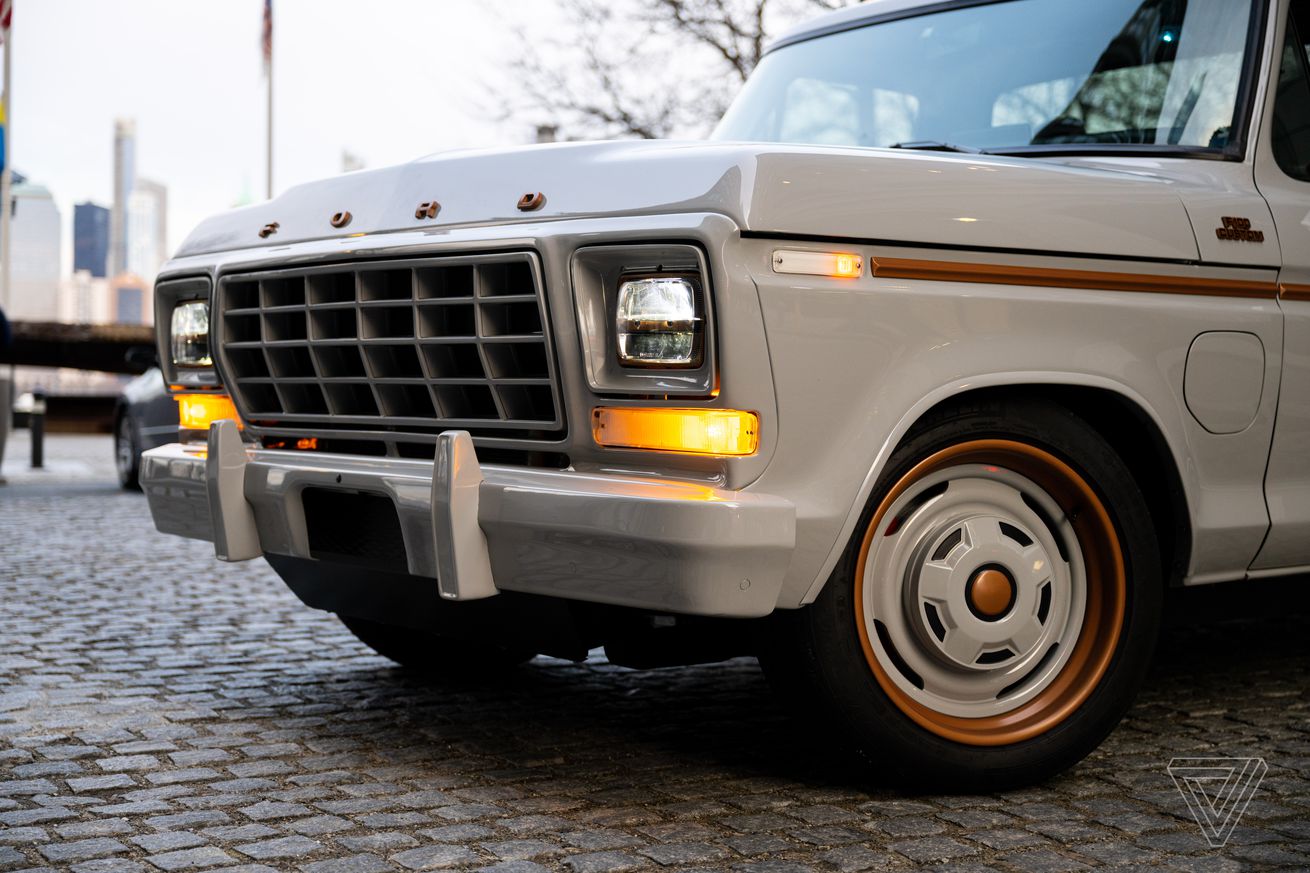 This is the front end of the Ford F-100 truck from 1978, but it’s restored with gray and copper accents. The LED headlights are on and you can see the new access door on the driver-side front fender that houses the charge port.