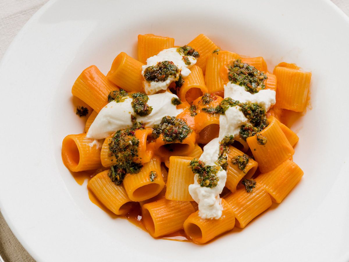 A white dish filled with short pasta in red sauce. 