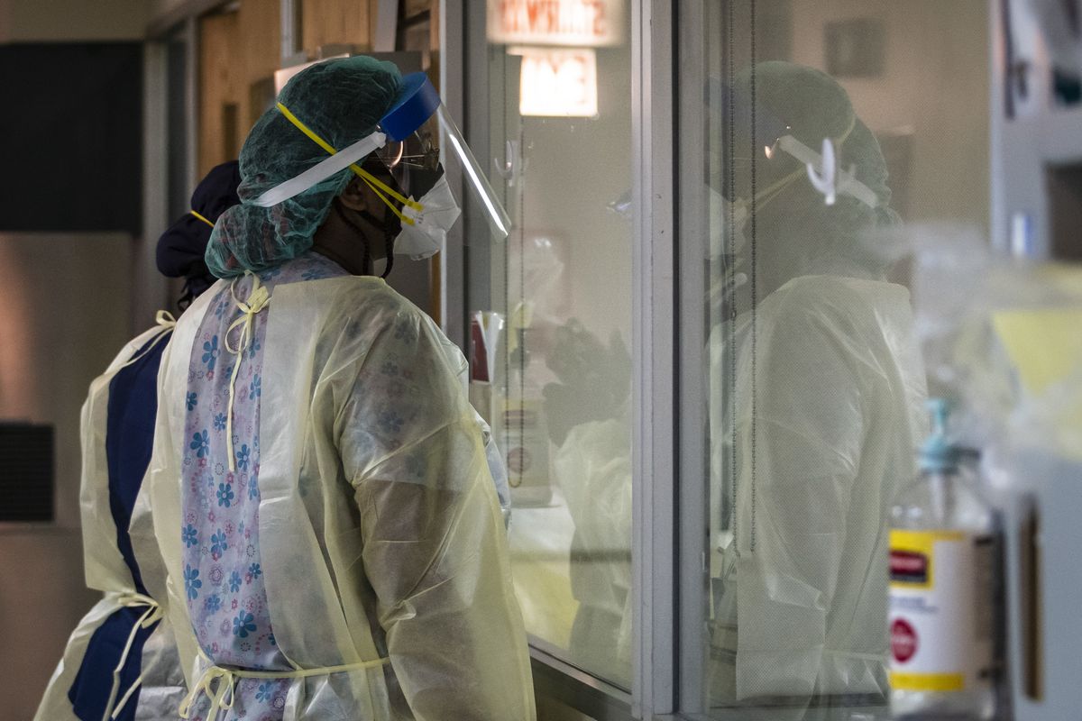 Nurses look through a window as they check on a man with COVID-19 and on a ventilator last fall at Roseland Community Hospital. Illinois’ coronavirus death toll stands at 22,599.