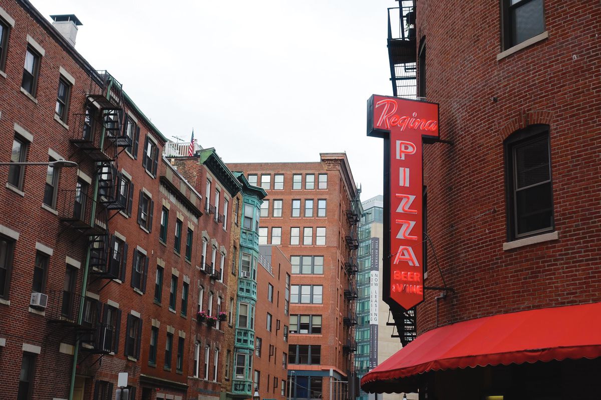 Red signage reading “Regina Pizza beer &amp; wine” outside of the original Pizzeria Regina location