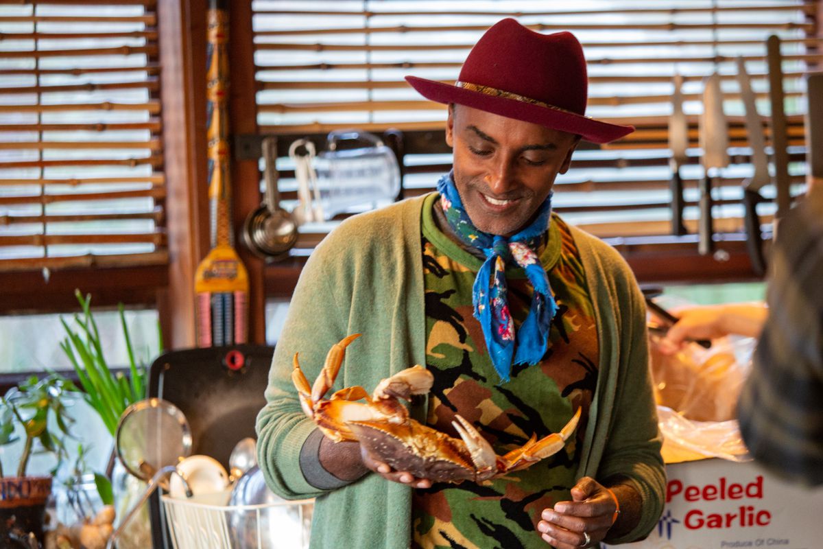 Host Marcus Samuelsson holding a crab in a home kitchen for the Seattle episode of No Passport Required.