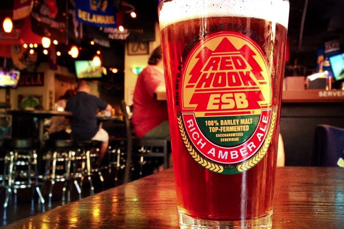 A glass full of Redhook’s ESB amber ale on a wooden bar.