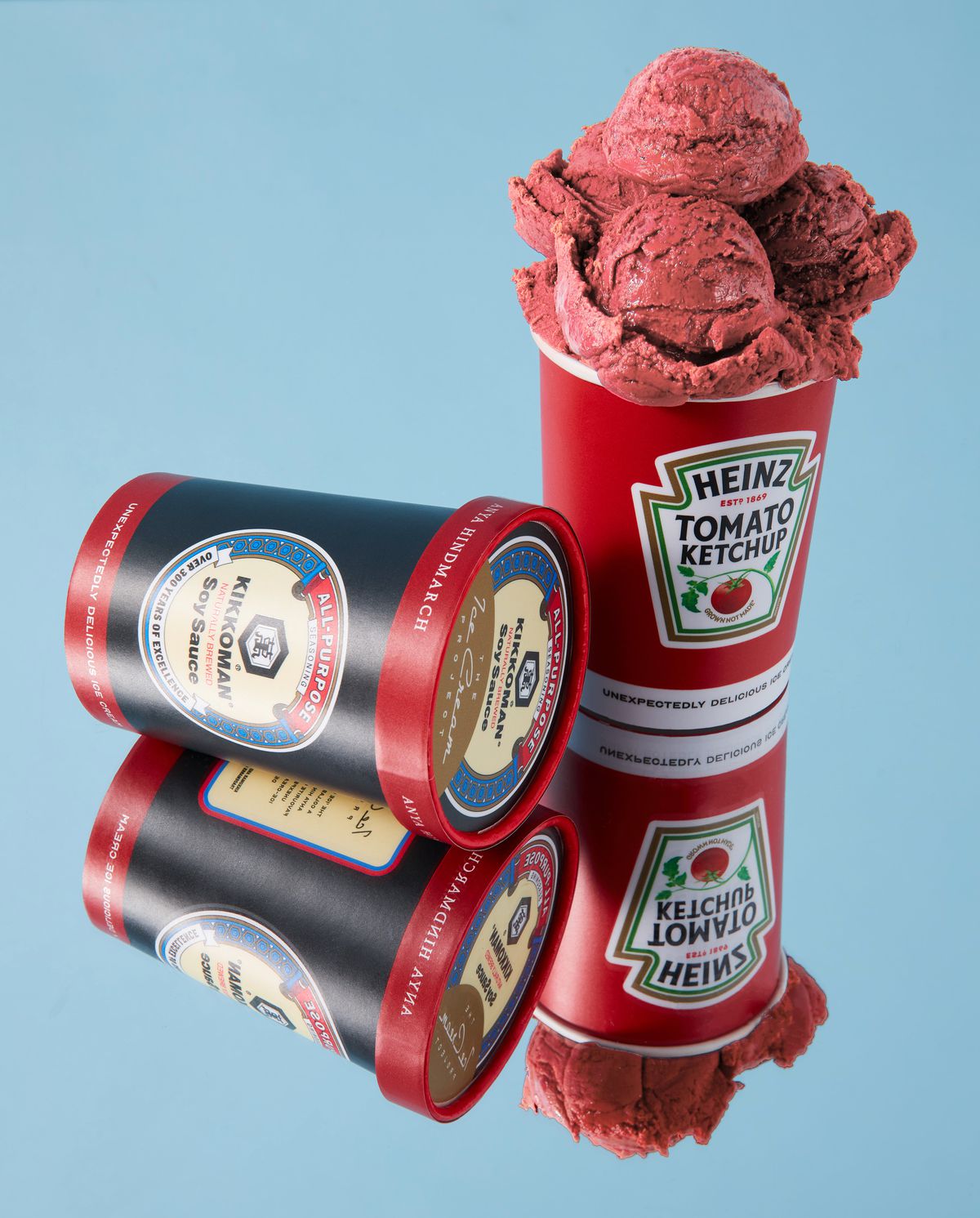 An open container of Heinz Ketchup ice cream showing off large red scoops, beside a closed container of Kikkoman soy sauce ice cream.
