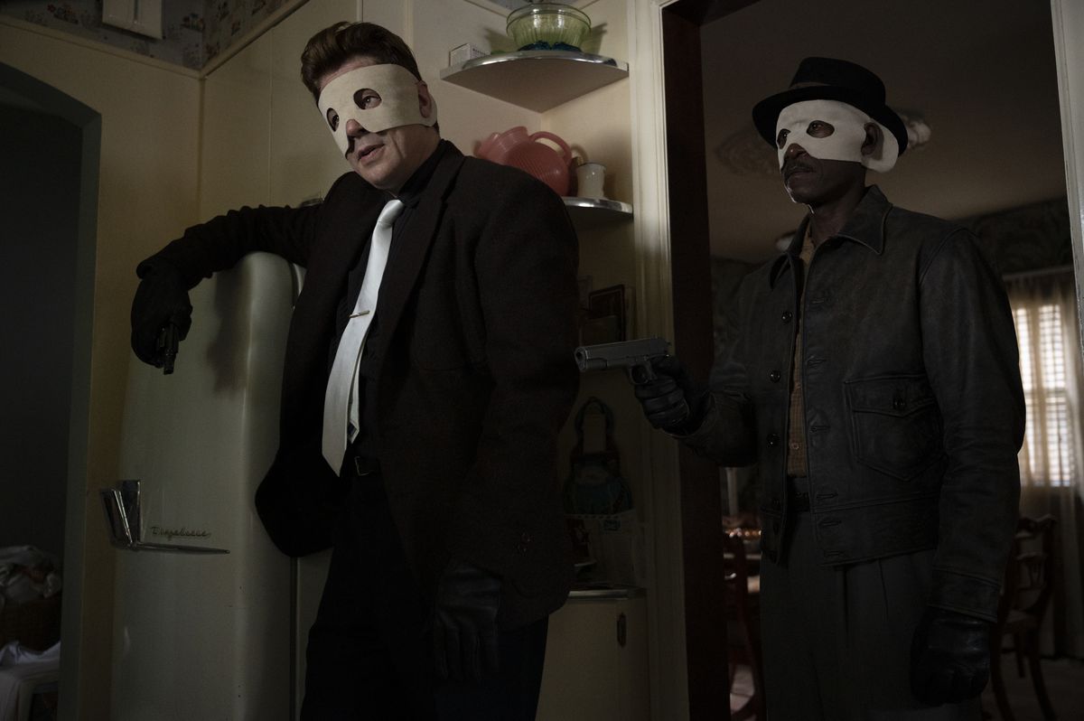 Benecio del Toro and Don Cheadle in dark suits and terrible white felt masks in No Sudden Move