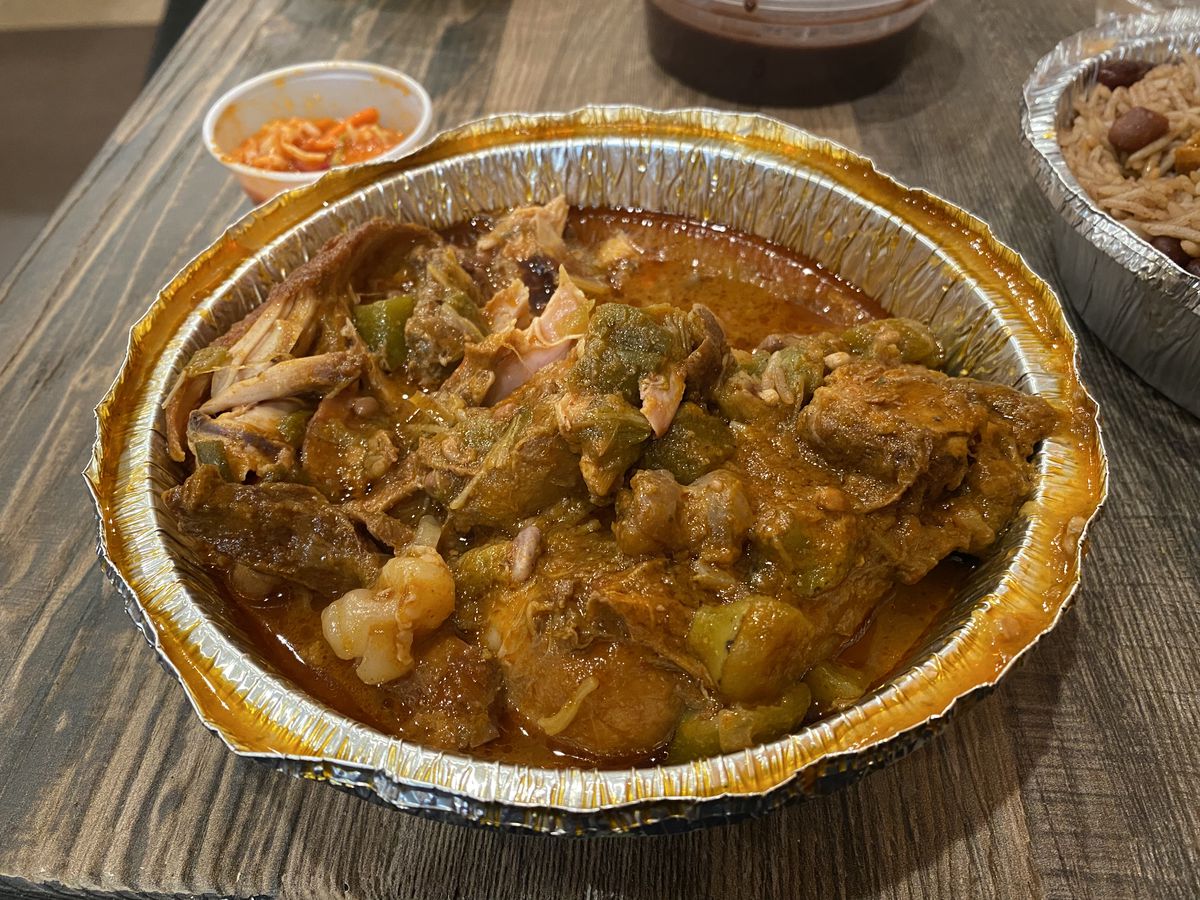 Fried chicken and bits of collagen and stewed okra bathe in an aluminum takeout container at Joenise, a Haitian restaurant in Crown Heights.
