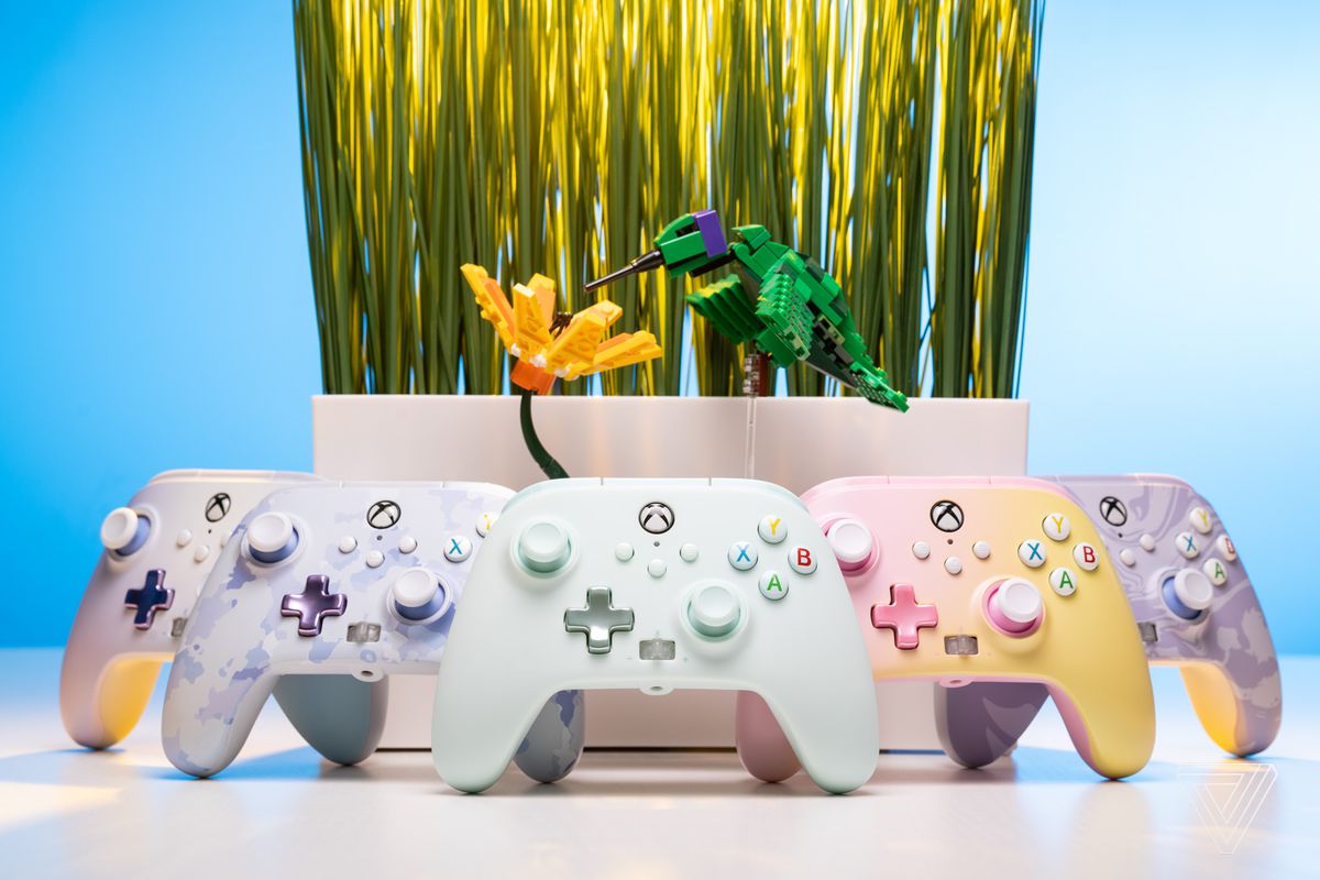 A lineup of five colorful pastel controllers in front of a decorative centerpiece.