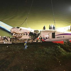 The mangled fuselage of a TransAsia Airways commercial plane is dragged to the river bank after it crashed in Taipei, Taiwan, Wednesday, Feb. 4, 2015. The Taiwanese commercial flight with 58 people aboard clipped a bridge shortly after takeoff and crashed into a river in the island's capital of Taipei on Wednesday morning.