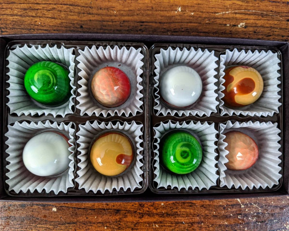 A box of eight fancy, shiny chocolates, two each of four different flavors