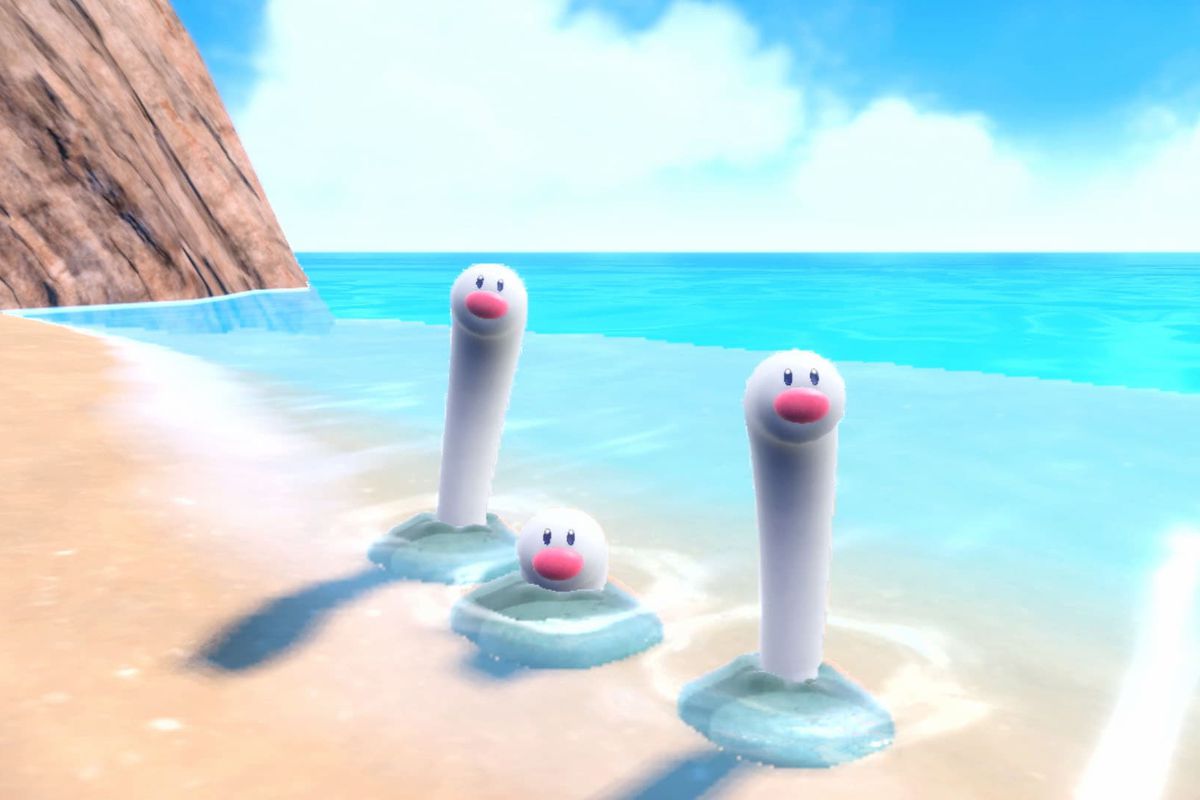 A trio of Wiglett —&nbsp;a white, lengthier version of Diglett — emerges from the sand of a beach in a screenshot from Pokémon Scarlet and Violet.